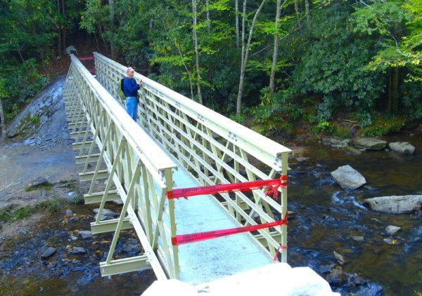 A new 80-foot bridge across Boone Fork Creek on the Mountains-to-Sea Trail opened today near Blowing Rock. Trail volunteer Drew Koehler of Watauga County enjoys the view. Photo by Randy Johnson