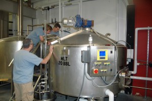 Paris looks on as brewers Paul Thompson and Drew Gibson make a new batch of brew.