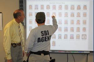 Law enforcement look at a projector featuring all of the suspects. 