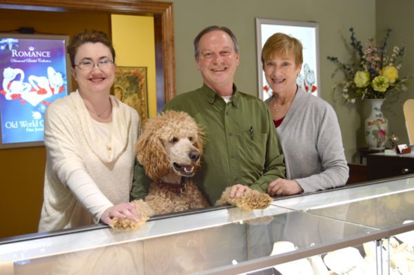 When you shop at Village Jewelers, you're bound to be greeted by smiling faces, maybe even those of Boone and Ozzie, Charlie and Joy's standard poodles, who are important fixtures in the store. Pictured here are Charlie, Joy and Boone with employee and friend Jennie Trivette.