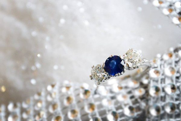 Three stone center set sapphire with old mine cut diamond side stones set in 18K white gold. Photo courtsey of Old World Galleries.