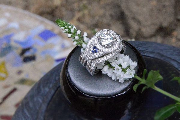 OWG helped create a new mounting for this diamond, which now features a diamond criss cross shank with a diamond halo and front and back diamond bands, as well as a trip of sapphires on each side for accent. Photo courtesy of Old World Galleries.