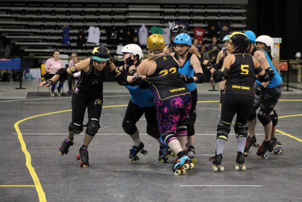 Jammer Public Jenemy No. 1 (Jenna Cucco) shirt whips off Tutu LaRue while pivot, Coco Janel No. 5 (Jennele Vaquera) blocks the pack of Dominion Derby girls. Photo by Kevin Gordon.