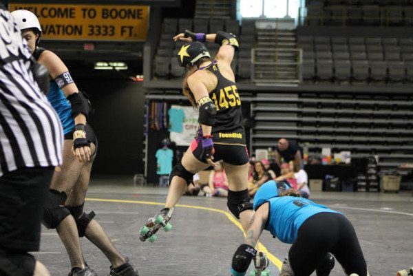 Jammer Feendish (Lauren Feeny) leaping past Dominion Derby Girl pivot. Photo by Kevin Gordon.